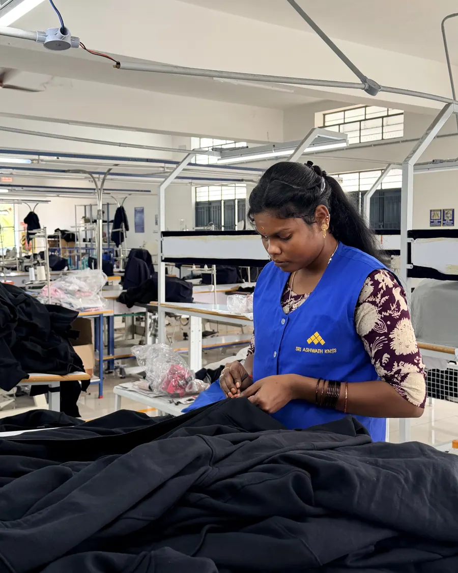 A checker inspecting a stitched garment against the approved sample